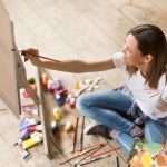 Young woman painting on canvas