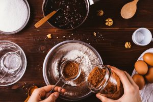 Female's hands sift cocoa powder into bowl