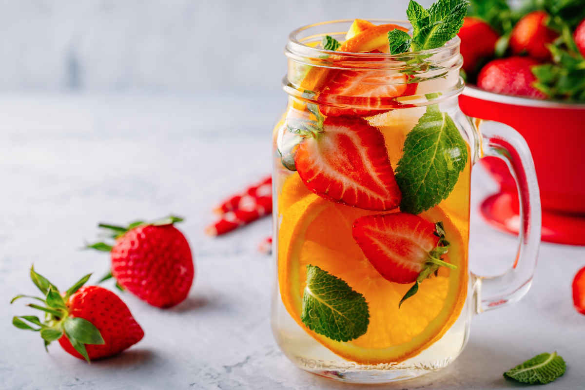 Infused detox water with orange, strawberry and mint. Ice cold summer cocktail or lemonade.