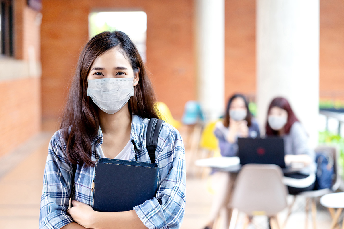 Portrait of young asian student wear mask looking at camera hold