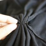 A questo punto tirate verso il centro del vestito entrambi i tagli e cucite per fermare il tutto dando alle aperture una forma quasi triangolare.