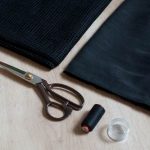 Minigonna, cotone nero, forbici, tessuto di cotone a rete e spilli.