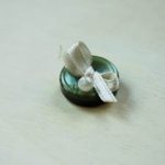 Tagliate la parte finale dei nastrini trasversalmente e incollate qualche perilina sotto il nodo del fiocchetto