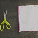 Sistemate il templete per i petali a forma di cuore su un foglio di carta crespa. Per tenere ferma la carta potete usare la spillatrice ai 4 lati del foglio del templete.