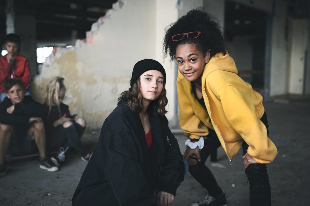 Group of teenagers girl gang standing indoors in abandoned building, hanging out.